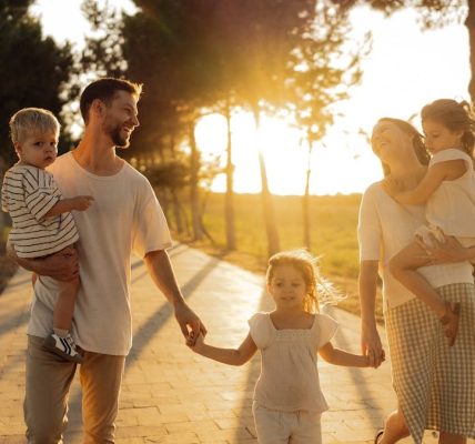 A joyful family walking together on a sunlit path during sunset, enjoying an outdoor stroll.
