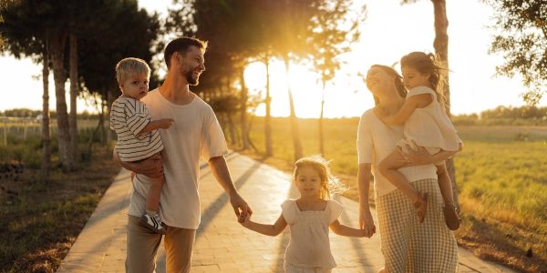 A joyful family walking together on a sunlit path during sunset, enjoying an outdoor stroll.